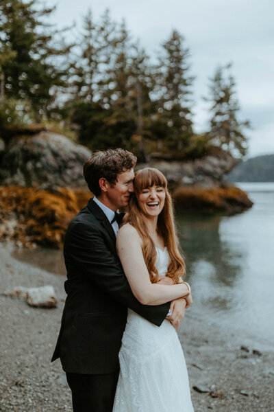 groom hugging bride from behind at their alaska beach elopement