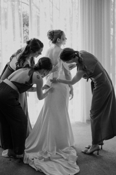 Bridesmaids doing up brides dress during yarra valley wedding