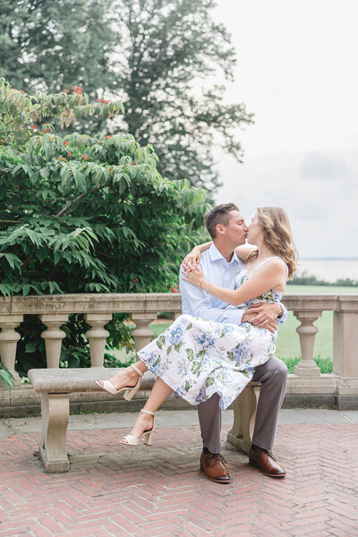 An engaged couple kiss on the balcony of Blithewold Mansion in Bristol, RI.