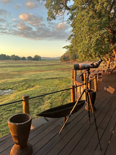 spotting scope on a deck looking over green fields