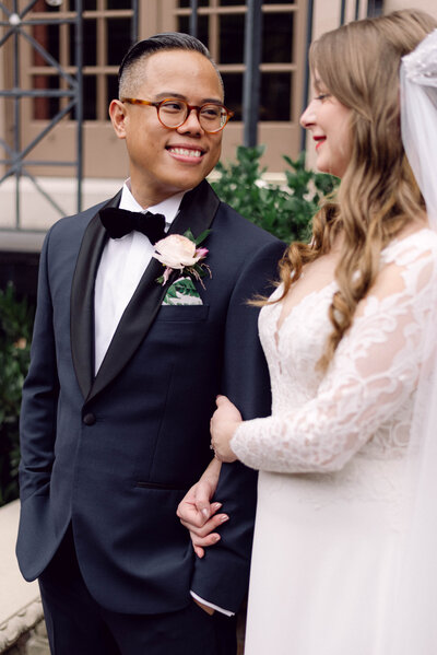 Bride looking down while holding onto the groom’s arm as he laughs during their Richmond, VA wedding celebration.