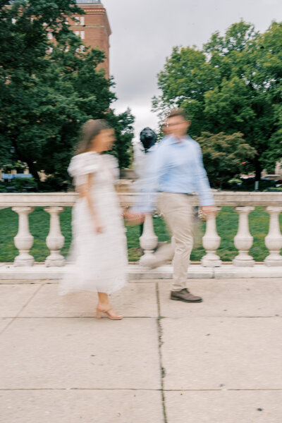 Motion blur photo of man and his Austin bride to be walking and holding hands photo taken by Austin wedding photographer