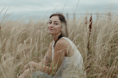 Heather smiles serenly in a meadow of tall grass