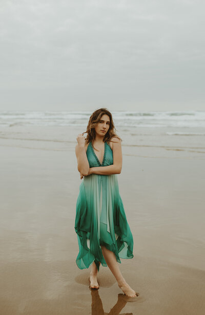 girl in green dress standing on oregon coast beach