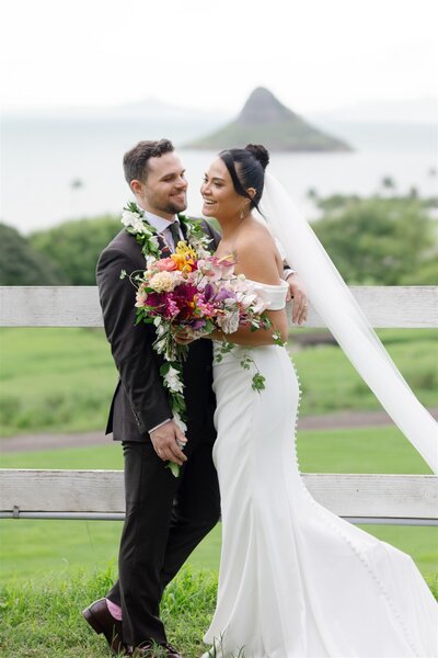 A person laughing with their partner and leaning into them on their wedding day 