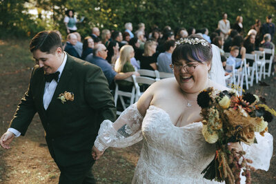 Two brides holding hands at their Oregon wedding as they walk away after their wedding ceremony.