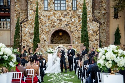 Outdoor wedding ceremony in front of stone building