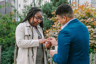 Romantic Paris proposal at Square Marcel Bleustein in Montmartre — man putting a ring on woman’s finger moments after she says yes.