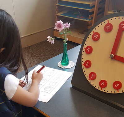 Montessori student writing on a paper in Burnaby Montessori classroom