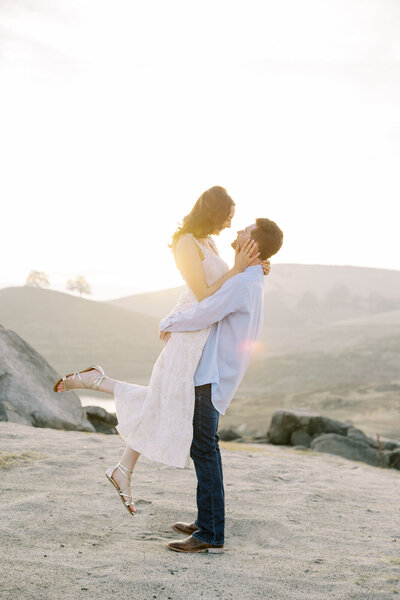 An engaged couple snuggles close in an open field for their engagement session