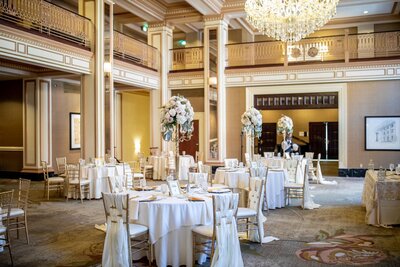 Elegant wedding reception setup in the historic ballroom at Omni Severin Hotel in downtown Indianapolis, with tall floral centerpieces and gold Chiavari chairs