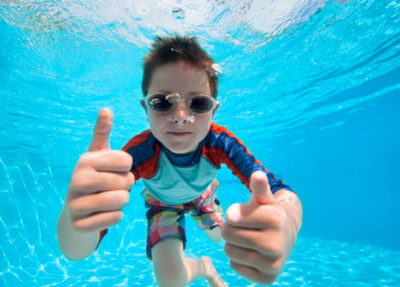 The little boy happily enjoys being underwater, finding delight in the pool