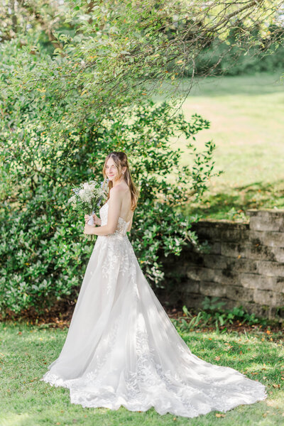 bride holding bouquet next to large bushes during wedding photo session in capital region  