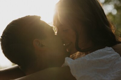 couple kissing with sun shining behind them