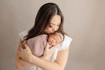 mom wearing white dress holding baby newborn girl