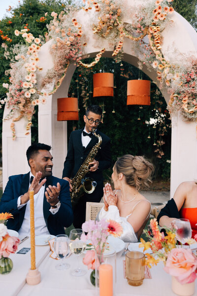 Bride and groom clapping during speeches at wedding planned by Bloom & Blueprint