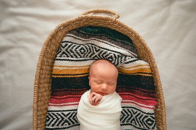 Swaddled baby in moses basket with native american blanket at a Houston Newborn Photography session