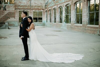 Bride embracing her Groom from the back as they are about to have their first look in the middle of am industrial venue