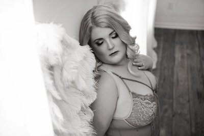 woman with large black wings prop posing in black and white boudoir portrait