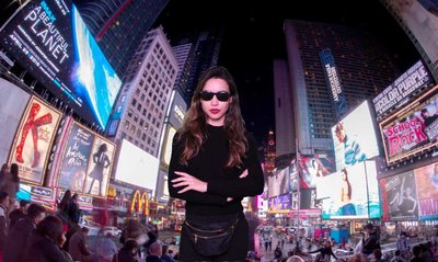 woman standing in the midle on time square on. a green screen photo booth