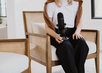woman holding podcast mic in chair