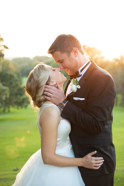 Bride and groom kiss on Blackhawk Country Club greens at sunset for wedding portraits.