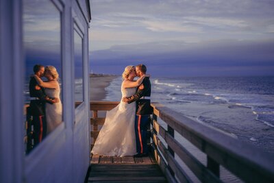 bride and groom kissing on deck above ocean