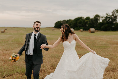Bride and Groom running towards the camera in a field - Alex Bo Photo