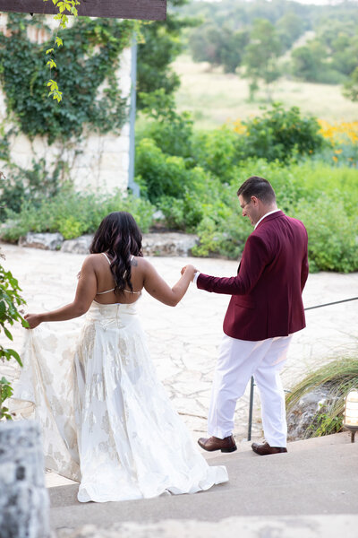 An Austin-based wedding photographer captures the magical moment of a bride and groom walking down a stone path.