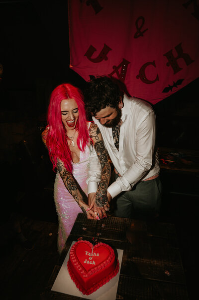 A tattooed couple cut their vintage vegas heart shaped cake at their Manchester wedding. 