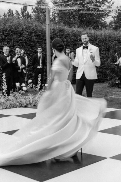 a groom twirls his bride in a greenery filled path