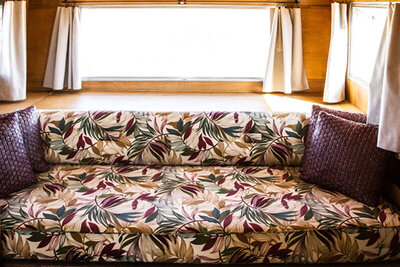 Location branding image interior mini airstream trailer bed with patterned bed spread two purple pillows