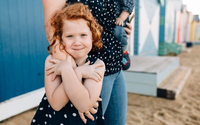 girl hugging mum's hand at beach during lifestyle family photography Melbourne And So I Don't Forget Photography