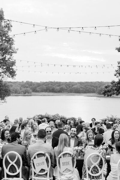 bride and groom sitting at the table with family and friends during rehearsal dinner on the lawn of the Wainwright House in Rye, NY