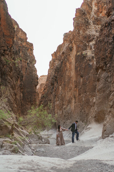 A bride and groom exploring a canyon desert landscape