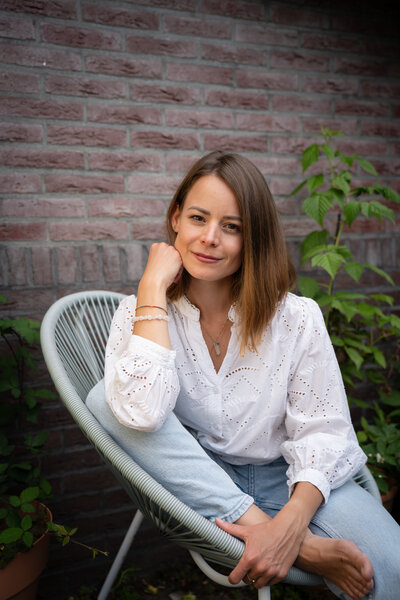 Livia, founder of Liv in the Flow, sitting outdoors with a warm, inviting posture, ready to help you take the next step toward personal growth. With a focus on holistic life coaching and stress relief, this image captures the supportive and action-oriented approach to empowering clients.