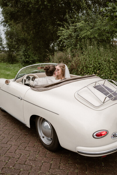 Bruid en bruidegom in klassieke trouwauto, cabrio