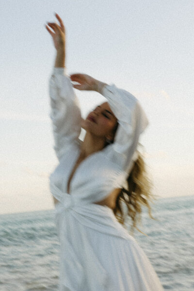 Bride dancing in the sunlight on a beach in Miami, FL for her bridal portraits before wedding day at Vizcaya Museum, captured by Andrea-Marie Photography