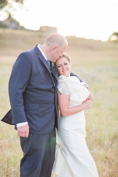 A couple embraces in a sunlit field, exuding warmth and intimacy, reflecting the natural elegance of an outdoor wedding planned by Socially Significant Events.