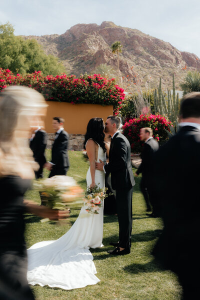 Sanctuary at Camelback Wedding Photographer and Videographer Bride and Groom Kissing While Bridal Party Walks Around Them