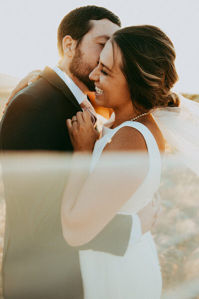 man kisses a woman's cheek in bridal attire
