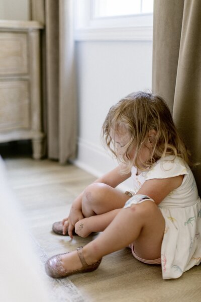 sweet little girl putting her shoes on the wrong feet