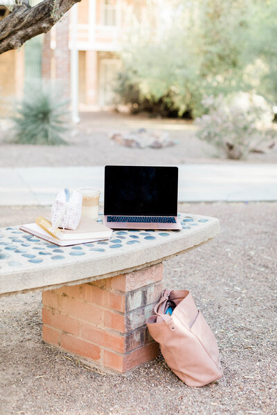 Laptop and coffee where Female Business owner is working outdoors.