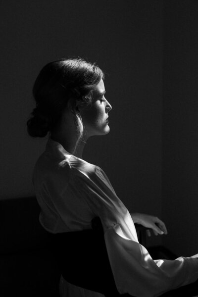 Bruid die wordt klaargemaakt tijdens de voorbereidingen - bruidsfotografie in sfeervol zijlicht