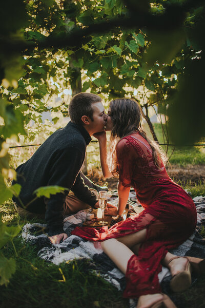 A man and woman kiss in the vineyard of Villa Bellezza