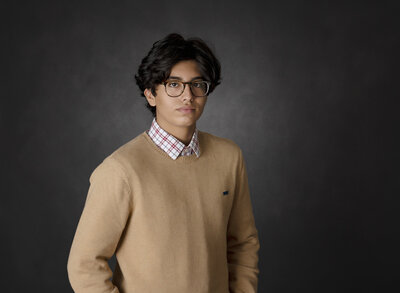 teenage boy with glasses on dark gray background