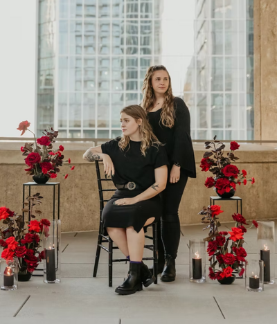 couple poses on charlotte rooftop with red flowers surrounding them