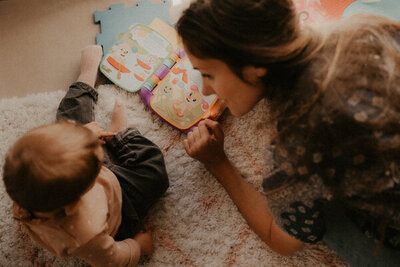 une maman lit un livre a son bebe dans la chambre