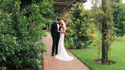 Bride and groom hold each other on a garden pathway