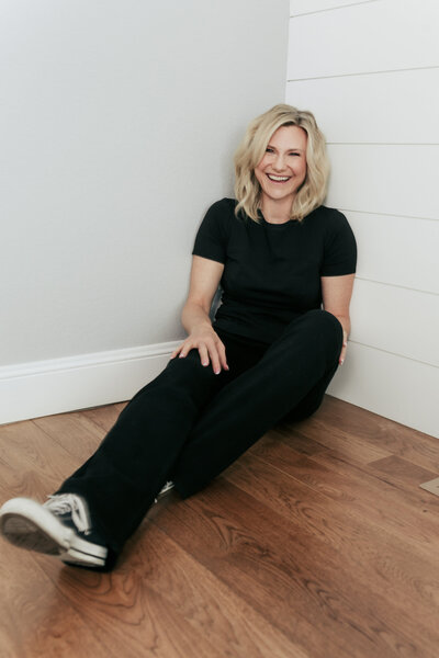 Kristin Tibbs seated in a neutral-toned chair, offering calm and strategic guidance for luxury homebuyers in Northern Colorado.